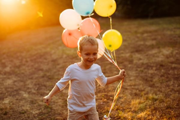 Guardians of Wonder: Preserving the Innocence of Childhood Young boy running with colorful balloons in golden light, symbolizing the wonder and imagination of childhood.