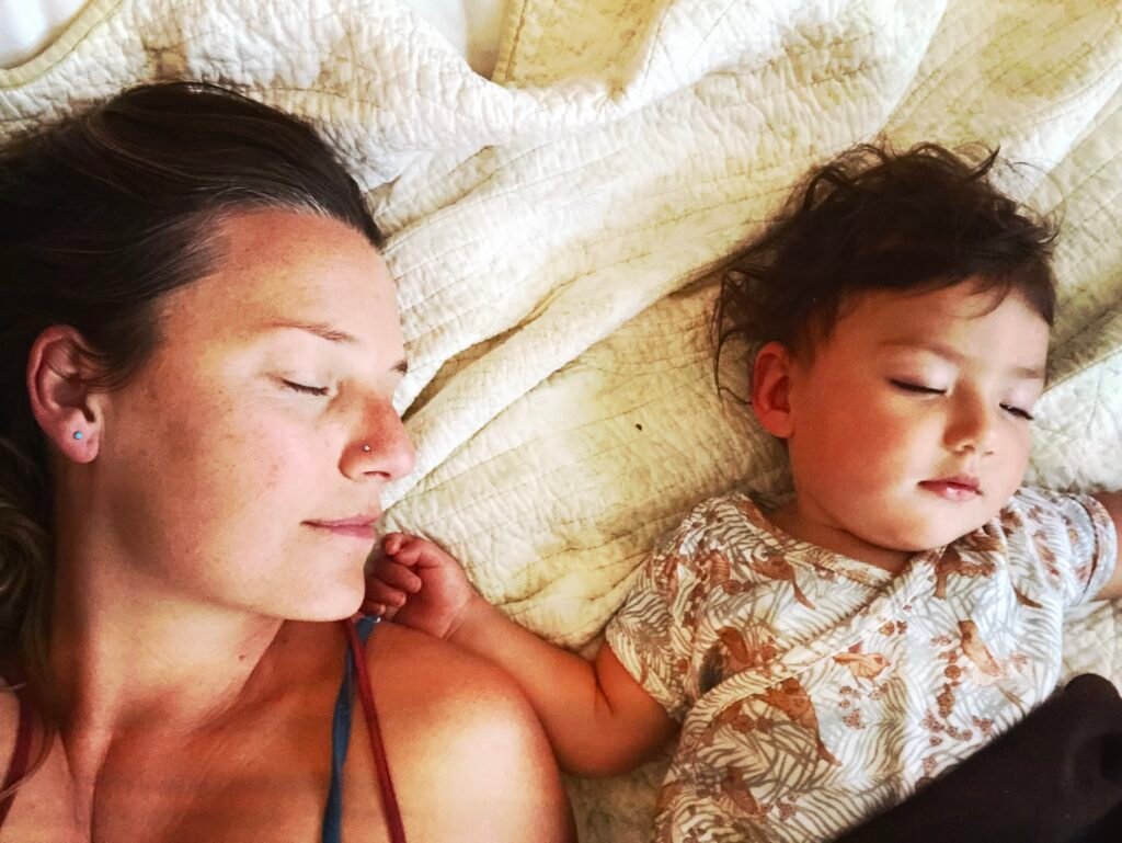 Mother and baby sleeping together on a soft quilt, capturing the quiet inspiration behind Little Guru & Co.