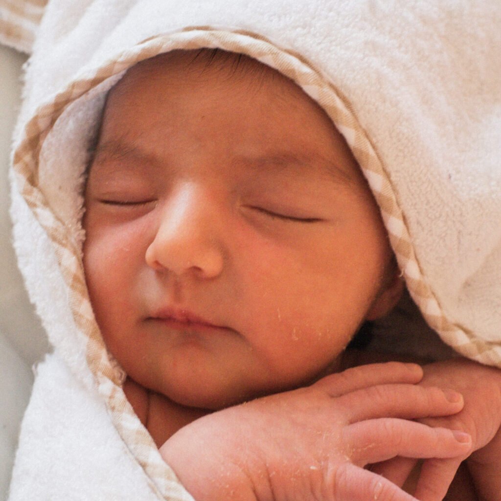 Newborn baby resting peacefully in a blanket, symbolizing the sacred beginnings honored by Little Guru & Co.