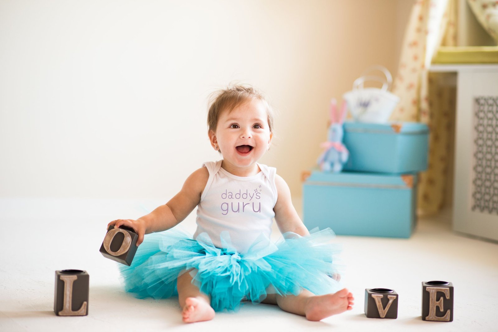 Our Ethics Smiling baby in blue tutu wearing an organic baby onesie bodysuit with "daddy's guru" slogan by Little Guru & Co.