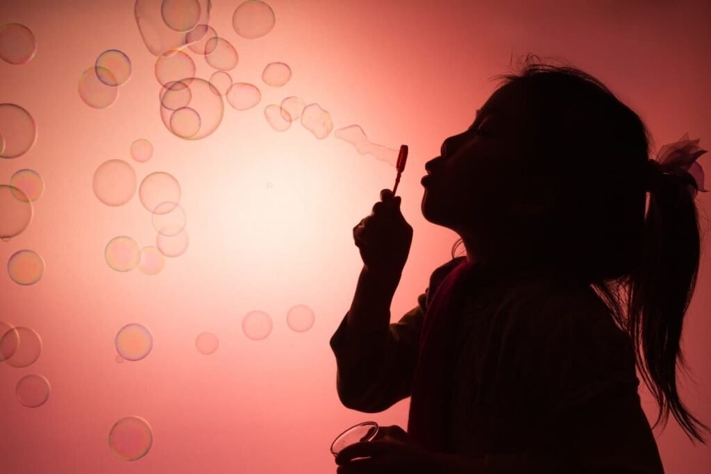 Child blowing bubbles at sunset, symbolizing imagination, play, and intuitive learning during the ages of openness.