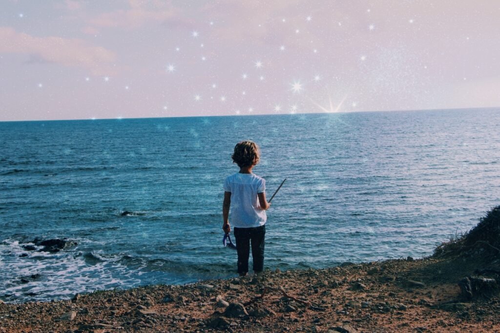 Born With a Blueprint: Your Child Arrived With Inner Wisdom Child standing at the edge of the ocean with stars shimmering above, symbolizing remembrance, intuition, and the blueprint children arrive with.