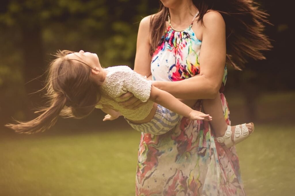 Parent lifting child in a joyful moment, showing attunement, emotional safety, and co-regulation in conscious parenting.