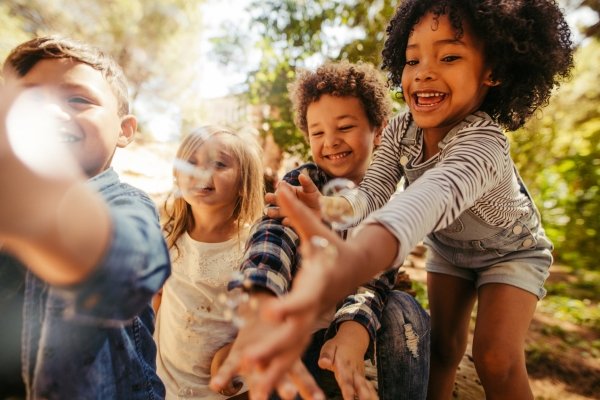 The Magic of Synchronicity: How the Universe Helps Us Find Our Way A group of children laughing and reaching forward outdoors, reflecting curiosity, trust, and following the signs together.