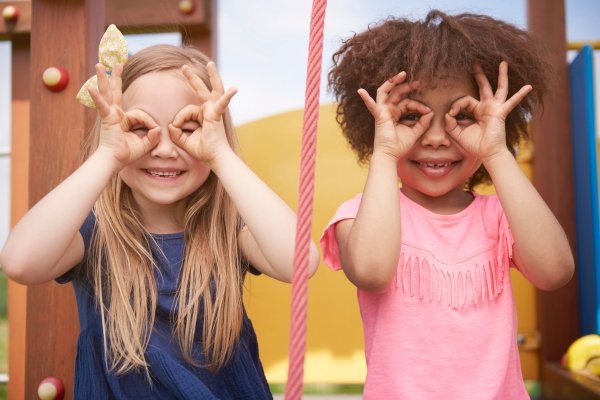 The Magic of Synchronicity: How the Universe Helps Us Find Our Way Two children playfully looking through their hands, symbolizing awareness, imagination, and seeing the world with fresh eyes.