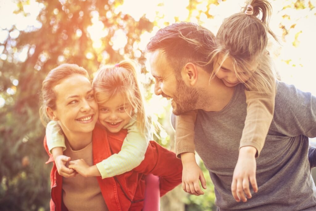 A joyful parent and child sharing a playful moment outdoors, symbolizing the magic of synchronicity and the way children guide us back into presence and trust.