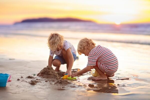 The Magic of Synchronicity: How the Universe Helps Us Find Our Way Two children playing freely at the beach during sunset, representing unstructured play, trust, and intuitive exploration.