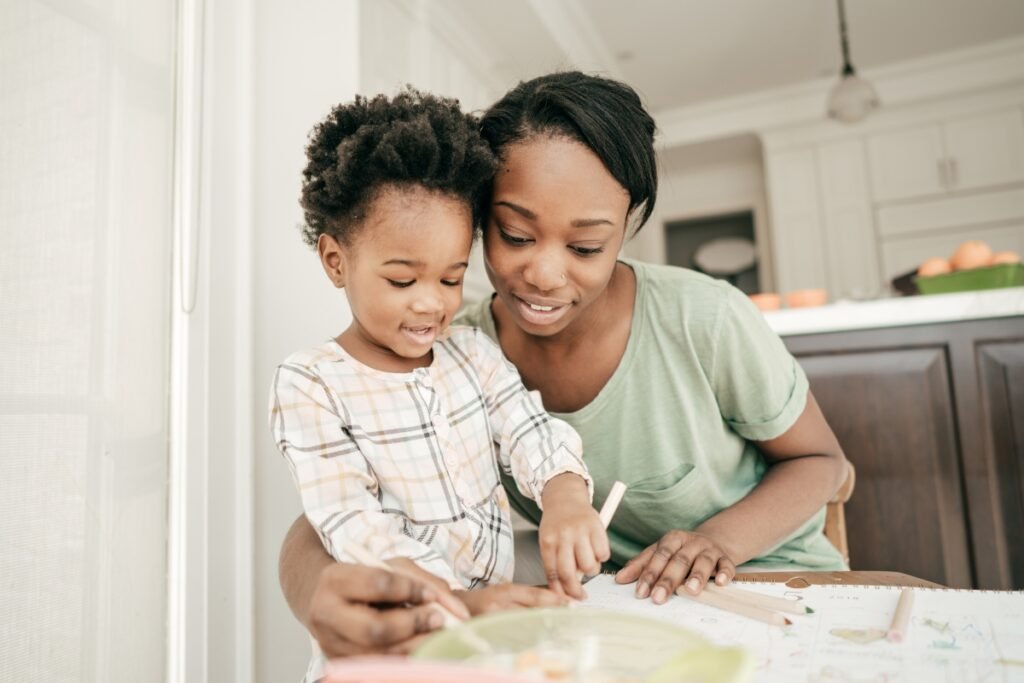 Mother using positive parenting language while drawing with her child at the table.