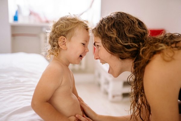Mother using positive parenting language while laughing and connecting with her toddler.