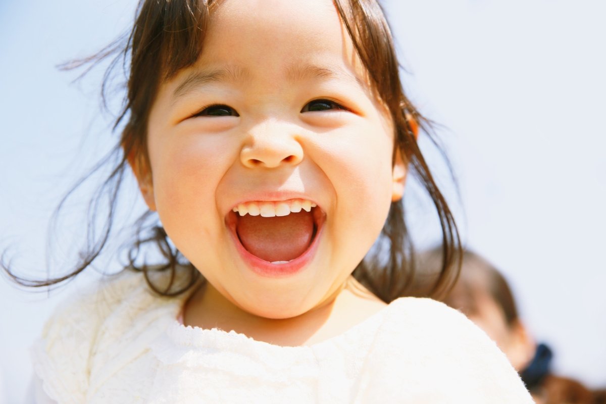 Close-up of a laughing child outdoors, expressing innocence, wonder, and the essence of early childhood