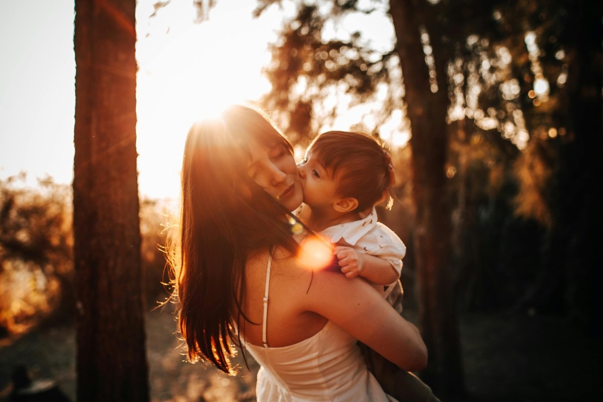 Mother holding her baby in warm golden light outdoors, reflecting attachment, connection, and spiritual parenting