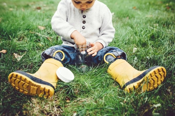 Child exploring insects in jar representing curiosity and learning through nature
