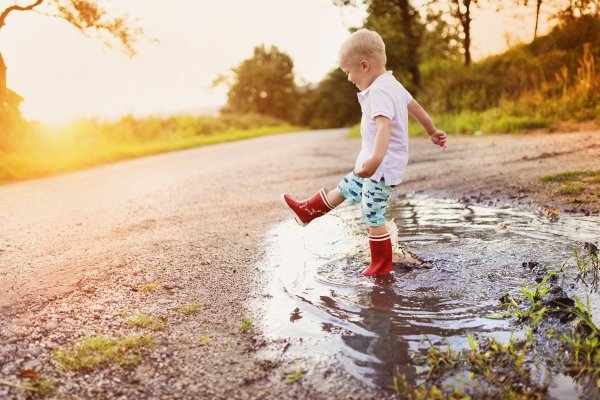 Child jumping in a puddle outdoors symbolizing curiosity and joyful childhood exploration