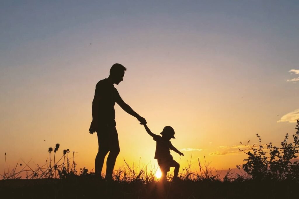 Parent guiding child by the hand at sunset, symbolizing trust, connection, and intuitive parenting