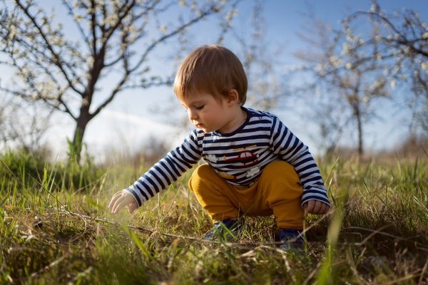 Child exploring grass in a meadow — connection to nature and raising conscious children