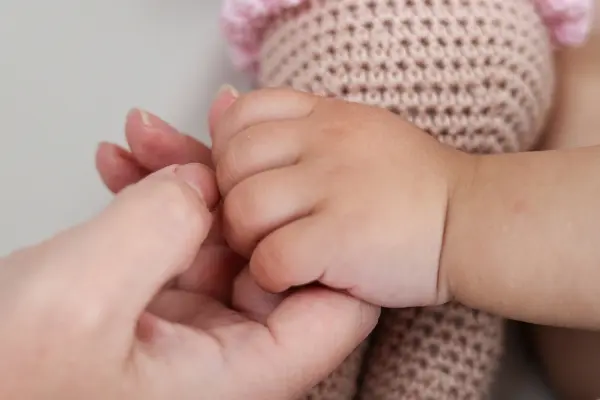 Baby holding a parent's finger, illustrating attachment theory, trust, emotional bonding, and parent-child connection.