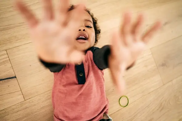 Toddler reaching toward a caregiver during an emotional outburst, representing the child as a mirror for healing.