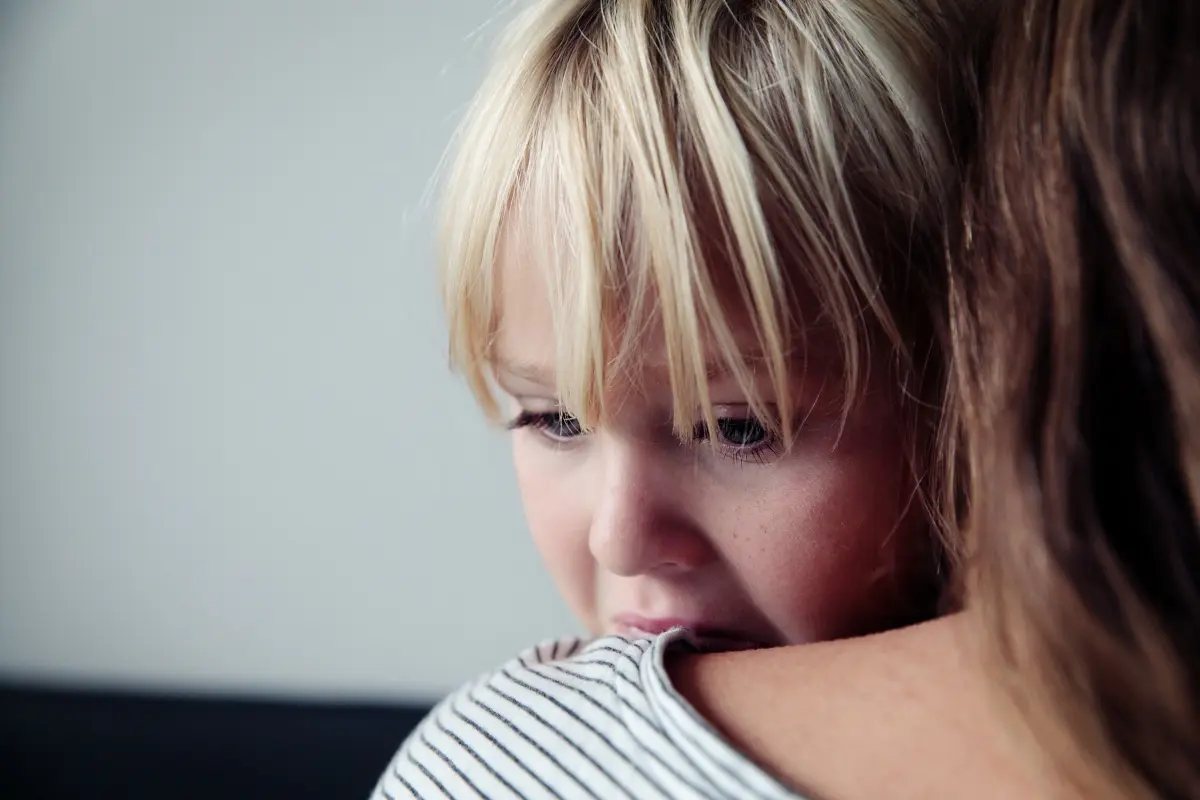 Child being held by caregiver during emotional moment, demonstrating nervous system regulation and co-regulation.