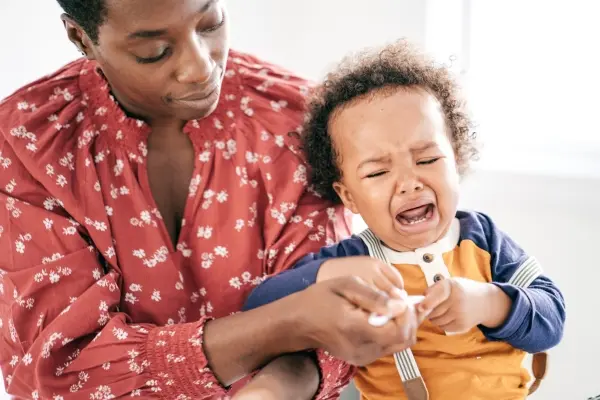 Parent practicing co-regulation while comforting an upset toddler during a difficult moment.