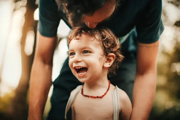Father playing with laughing toddler, illustrating secure attachment, joyful connection, and conscious parenting.