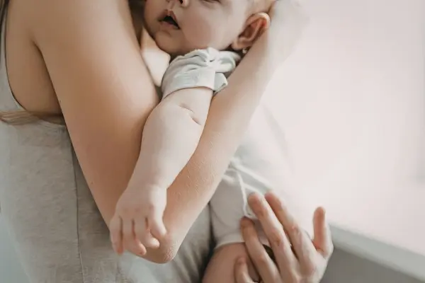 Mother holding sleeping baby, representing secure attachment, nurturing, and healing childhood wounds through parenting.