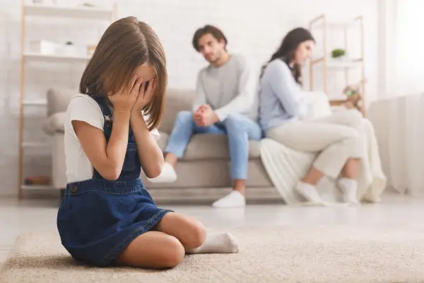 Child sitting alone while parents argue in the background, illustrating parenting triggers and emotional healing.