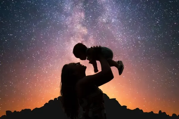 Are Humans Made of Stardust? The Science & Soul Explained Parent holding a baby beneath a star-filled night sky, representing how humans are made of stardust.